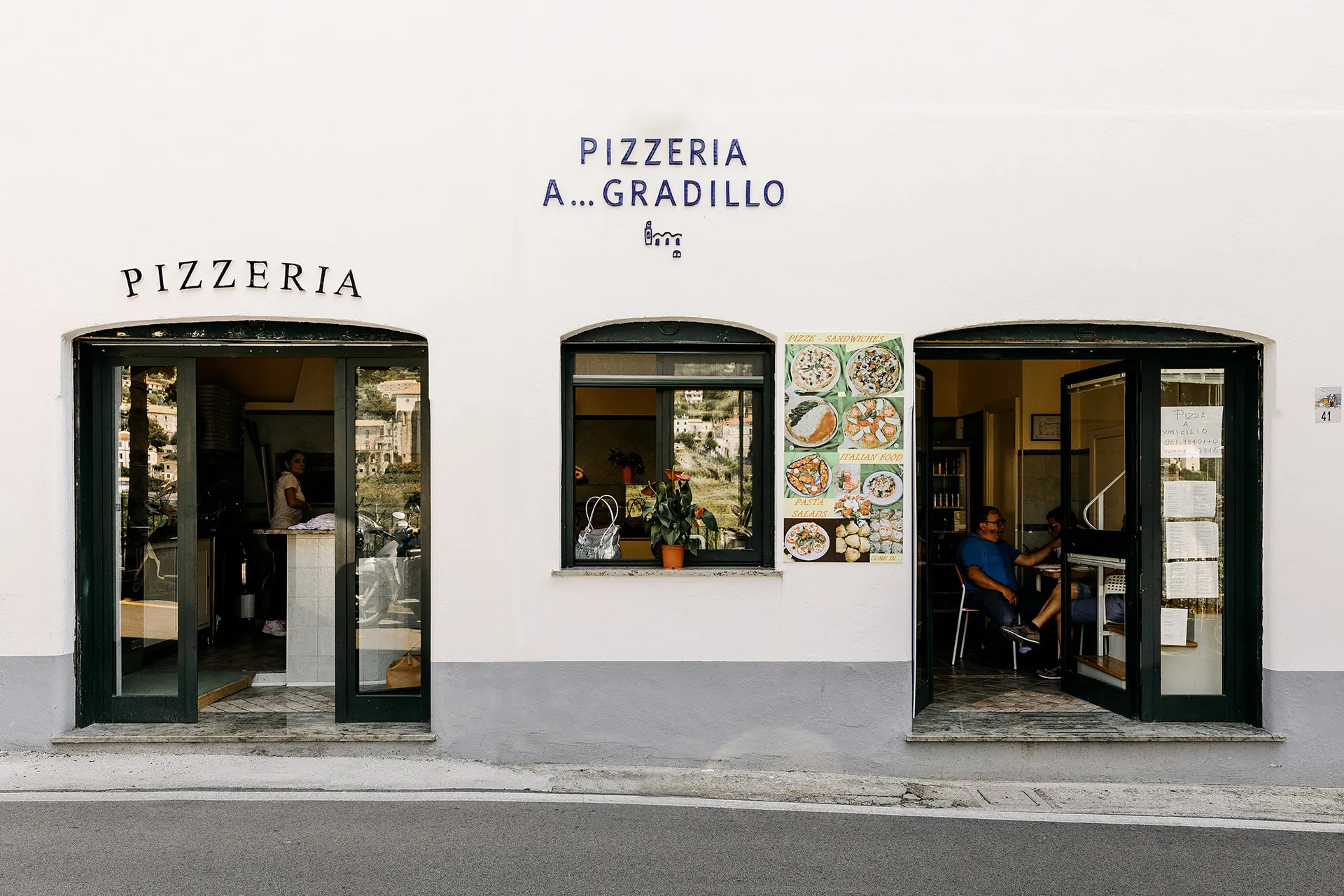 La facciata della pizzeria con le due porte ad arco e le scritte blu
