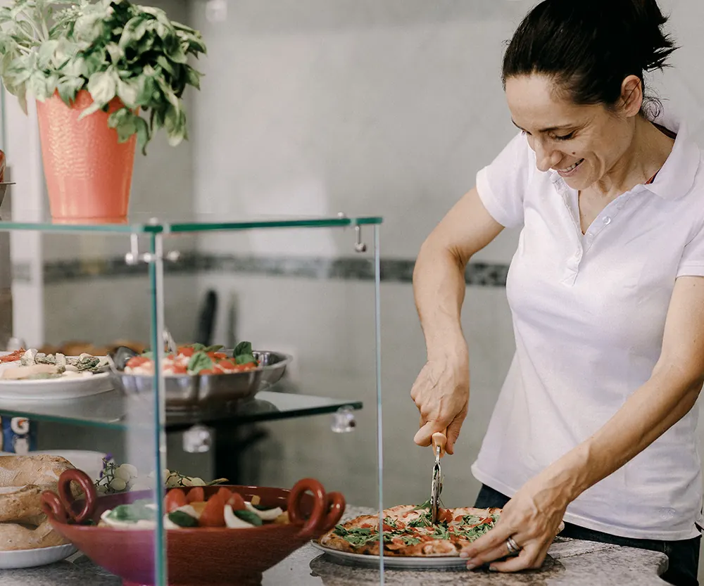 Una cuoca prepara un piatto al banco
