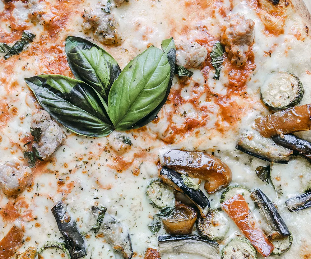 Una pizza con melanzane, zucchine e basilico